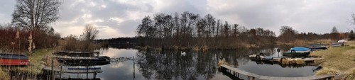 A calm lake with jetties and boats, surrounded by barren vegetation and clear skies, Berlin