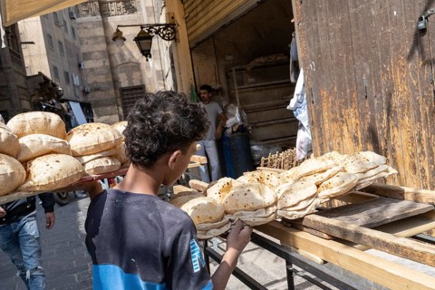 Cairo, Egypt. April 15th 2025. An Egyptian boy delivers baked traditional Baladi flat bread to a