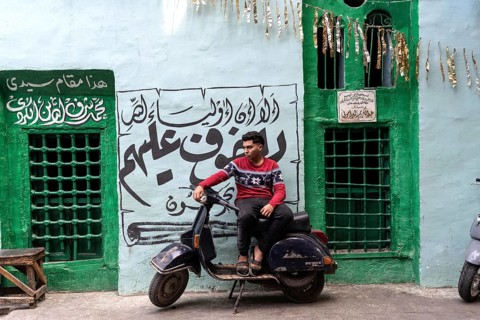 Cairo, Egypt. April 15th 2025. A young Egyptian man sits on a motor scooter outside a brightly