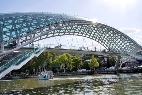 Tbilisi, Georgia. August 26th 2025. Tourists cross The Bridge of Peace over the Kura River also