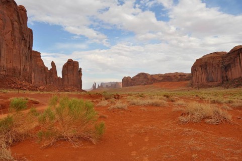 Wide valley with high rock walls surrounded by dry, red landscape, Monument Valley, Navajo Tribal