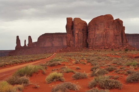 Majestic sandstone cliffs rise in a vast desert landscape under cloudy skies after a heavy
