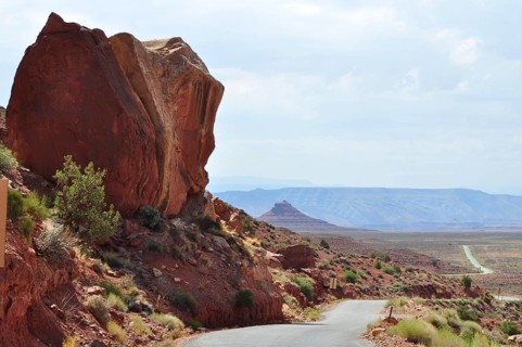 Large rock juts out next to a road in a vast desert landscape, Monument Valley, Navajo Tribal Park,