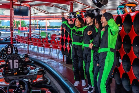 Diverse friends in racing suits celebrating with fists pumped up, feeling excited and happy after