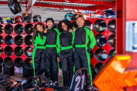 Diverse group of young adult friends smiling and posing in go kart racing suits, ready for an