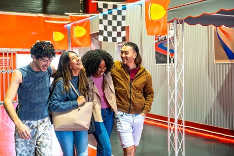 Diverse group of smiling young adult friends having fun and embracing casually while walking