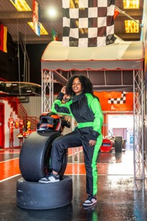 Young african american woman posing confidently in a neon green and black racing suit and helmet,