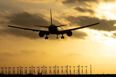 Boeing 777 commercial passenger jet aircraft in flight on approach to land over runway lights