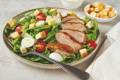 Caesar salad, with duck breast, on a light plate, on a light background, homemade, no people