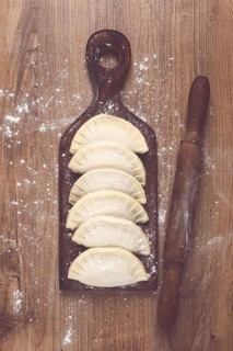 Raw chebureks, mini, on a cutting board, wooden table, close-up, no people
