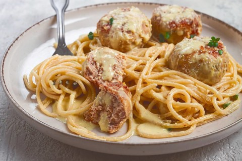 Spaghetti with chicken meatballs, with cream sauce, and parmesan cheese, and decorated with