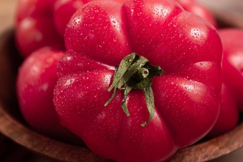 Pink tomatoes, in a rustic wooden bowl, close-up, no people