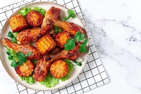 Fried chicken drumsticks, Mexican style, with corn, on a plate, close-up