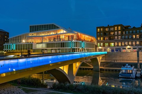 Primark on Maasboulevard and illuminated bridge across the city harbor in Venlo at dusk, the
