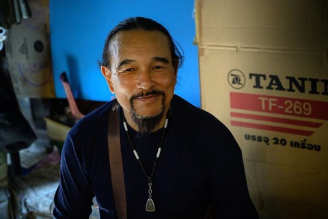 Mae Klong, Thailand. March 15th 2025. A smiling Thai market trader with an amulet necklace, at the