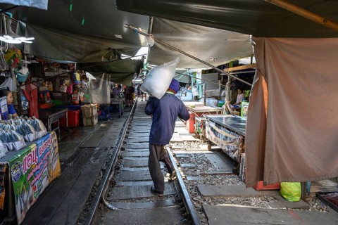 Mae Klong, Thailand. March 15th 2025. A market trader carries a bag of ice in the Maeklong Railway