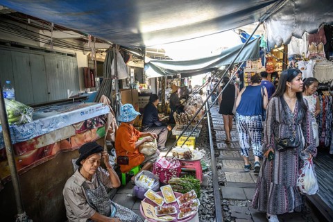 Mae Klong, Thailand. March 15th 2025. Tourists wander along the train rail lines with Thai market