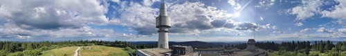 Panoramic view of the Schneeberg with the Backöfele, a high tower under a sunny sky full of clouds,