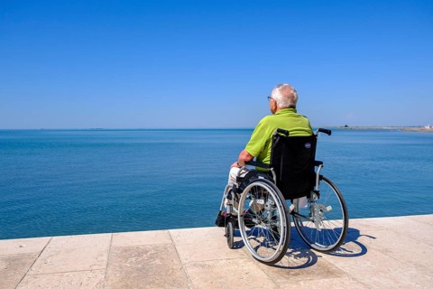 Senior in wheelchair looking at the sea, vacation with a handicap, Grado, Julian-Friuli, Adriatic