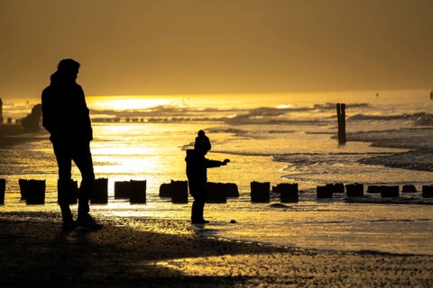Winter on the North Sea, sunset at sea, beach walkers, coastal protection, through wooden posts,