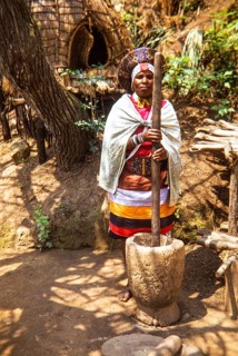 Zulu woman dressed in traditional attire, performing at outdoor cultural event likely in