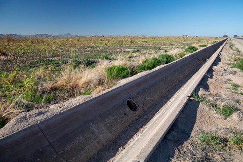Buckeye, Arizona - A an empty concrete irrigation ditch runs next to an unused field on a farm in