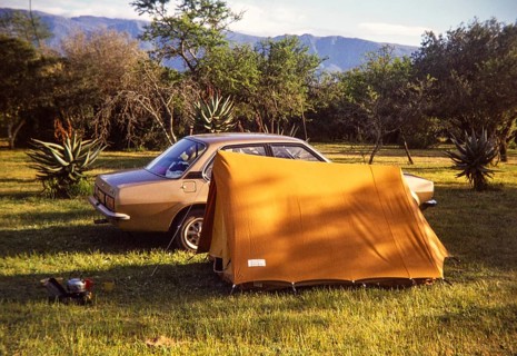 Car and small tent at campsite amongst tropical trees with camp cooking equipment, South Africa,