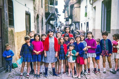 Group of children posing for photograph standing across a historic cobbled street, Portugal, Europe