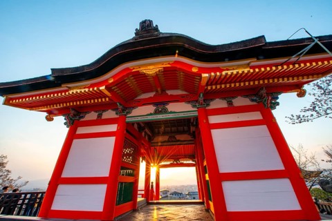 Sunset over the city with sun stars, view through the red Nishimon Gate, Kiyomizu-dera Temple, in