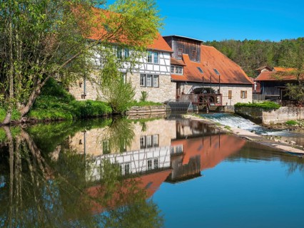 The historic water mill is reflected in the river Ilm, Buchfart, Weimarer Land, Thuringia, Germany