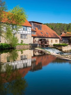 The historic water mill is reflected in the river Ilm, Buchfart, Weimarer Land, Thuringia, Germany