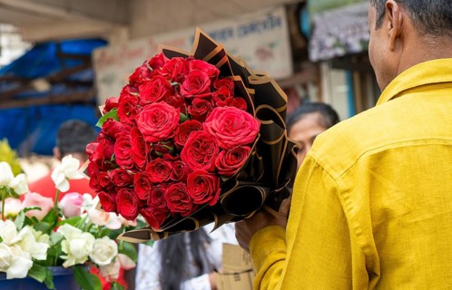 A customer holds a bouquet of red roses at a flower shop on Valentine's Day in Guwahati, India, on