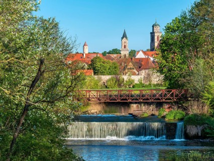 View over the Wörnitz river with weir to the historic old town with city wall and St. Georg