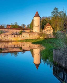 Digestive tower with park guard house on the city wall in morning light, reflection in the