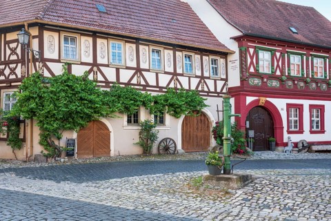 Street in the historic old town with half-timbered houses, cobblestones and hand pump, Alte