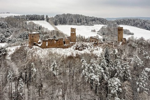 Medieval castle ruins in a snowy hilly landscape with forests, The Brandenburg in the Werra Valley