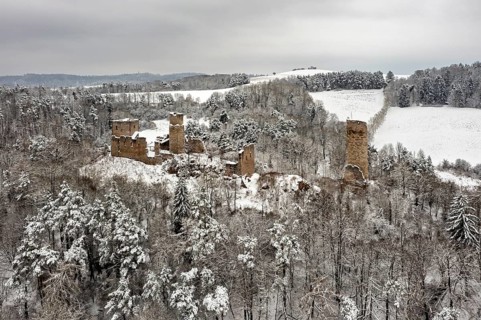 Snowy castle ruins in a wooded winter landscape, surrounded by rolling hills, The Brandenburg in