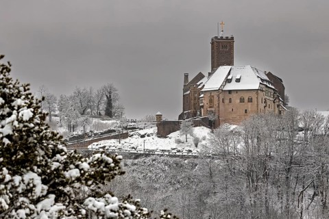 Snowy landscape with castle in the distance under grey sky, The Wartburg near Eisenach in Thuringia
