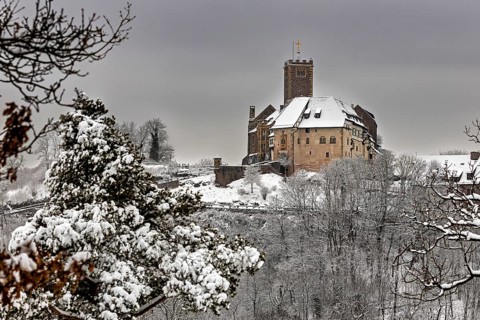 Medieval castle in winter with snow-covered forest and cloudy sky, The Wartburg near Eisenach in