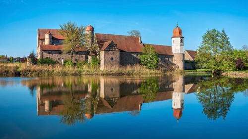 Perfect reflection of Sommersdorf Castle in a pond near Burgoberbach in the Altmühltal, Middle