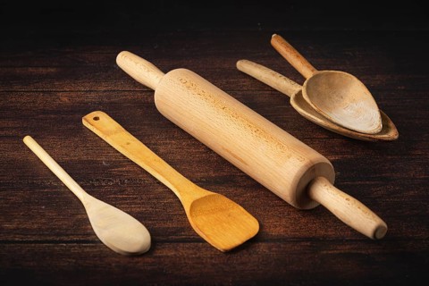 Rolling pin and wooden utensils on a dark wooden table in a rustic atmosphere