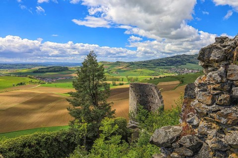 Ruins in front of a wide view of fields and hills under a cloudy blue sky, Mägdeberg Castle Ruins,