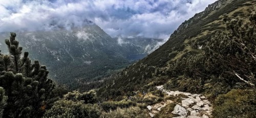 Wild mountain trail with a view of a lake, Morskie Oko and thick, dramatic clouds above the peaks,