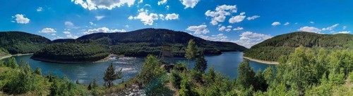 Panoramic view of Leibis Reservoir surrounded by forests and hills under a blue sky, hiking in the