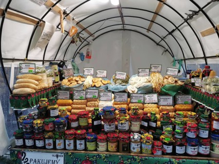 Colourful market stand with various types of jams and breads and local specialities under a tent,