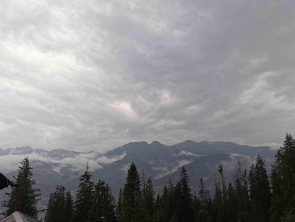 View of a mountainous landscape with clouds and conifers wrapped in fog, Zakopane, hiking in the