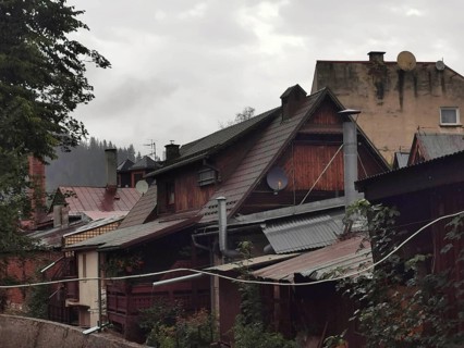 Old wooden rural buildings with various roofs and satellite dishes on a cloudy day, Zakopane,