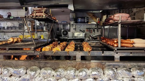 Large grill with various meats and local specialties over an open fire in a kitchen, Zakopane,