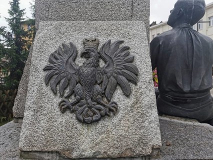 Stone monument with relief of the Polish white eagle, next to a human sculpture, Zakopane, hiking