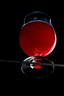A cognac glass with red liquid, dramatically illuminated, view from below